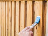 painting terrace railings with a blue paintbrush by hand